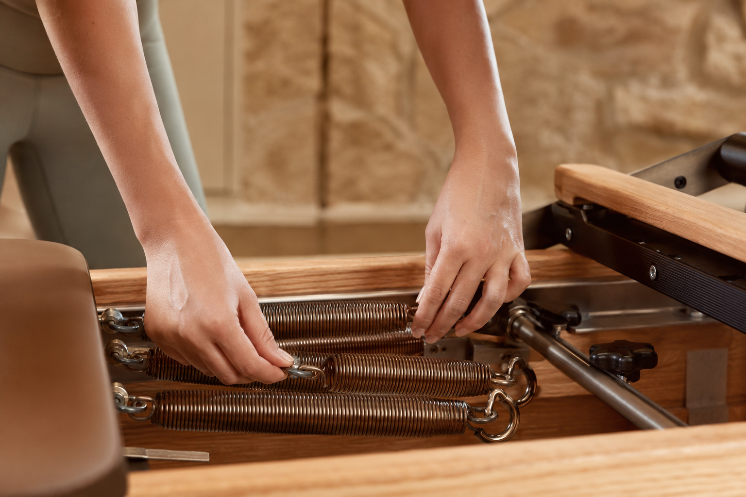 Réglage des ressorts d'un reformer en bois dans le studio Almaé